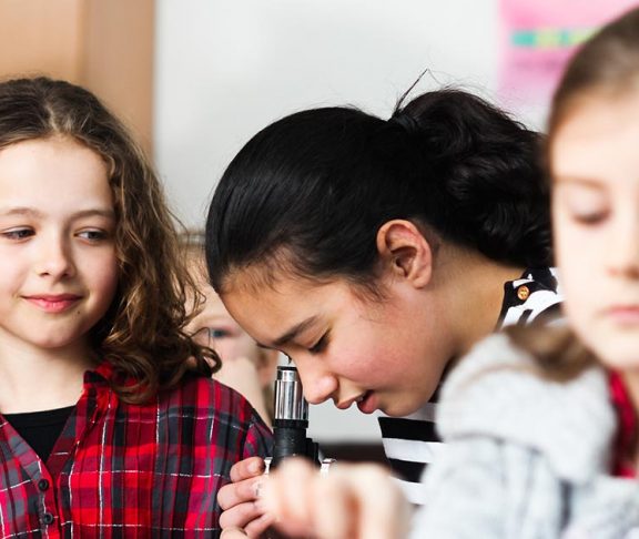 Meisjes in klaslokaal met microscoop