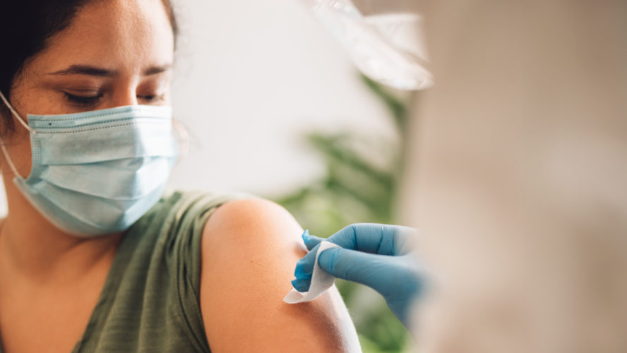 Woman getting vaccine at home. Healthcare professional cleaning and disinfecting female's arm before giving coronavirus vaccination shot at home.