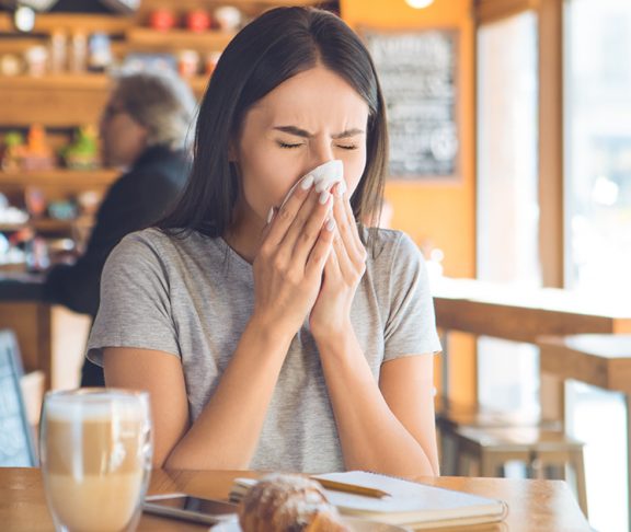 kobieta dmuchająca nos w kawiarni