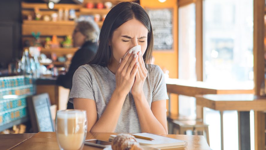 kobieta dmuchająca nos w kawiarni