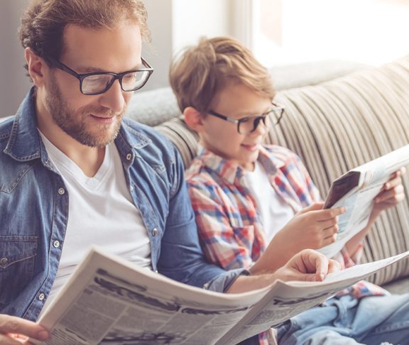 ojciec i syn w okularach czytający gazety