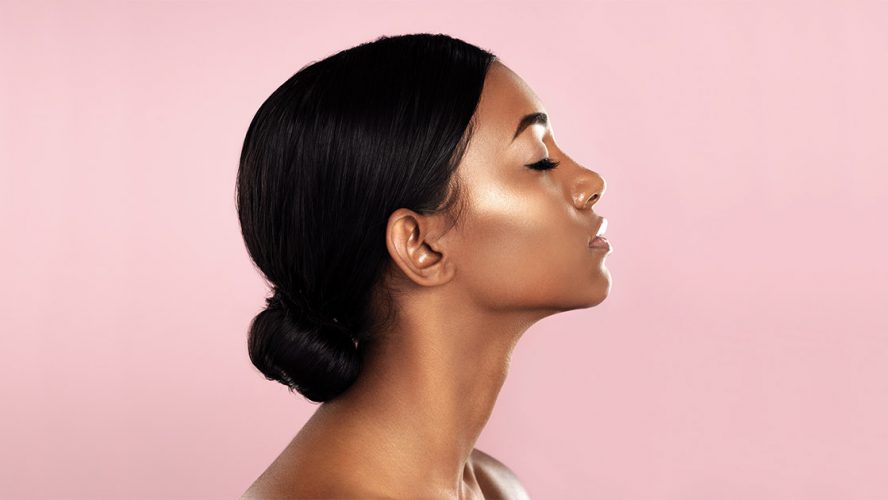Black woman with her eyes closed, in profile against a pink background