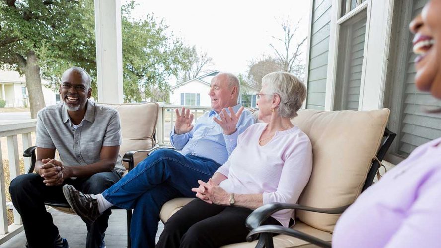 A group of seniors having a lively conversation on a porch