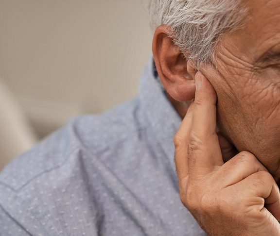 Elderly man pressing on his ear