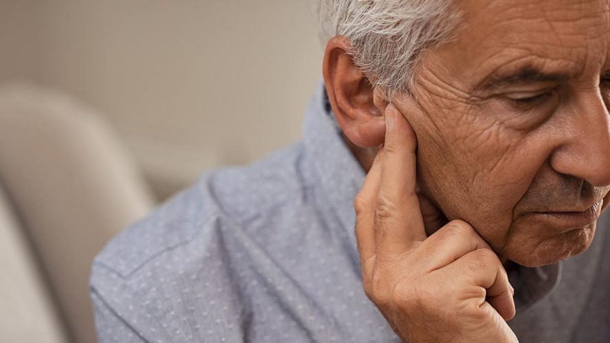 Elderly man pressing on his ear