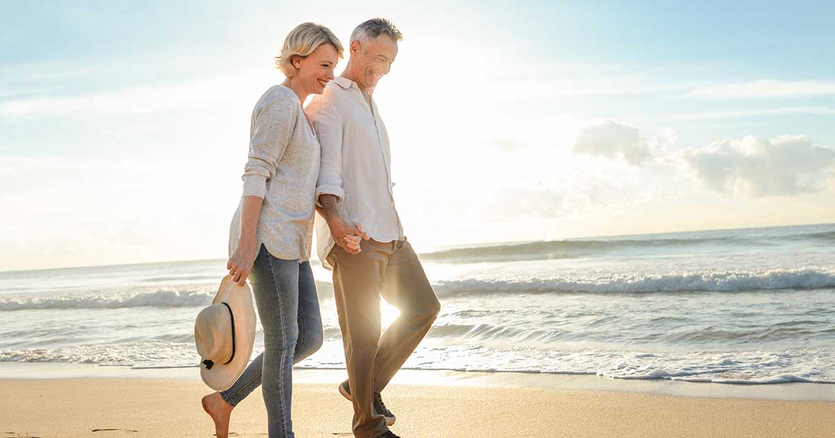 Mature couple smiling while walking on a beach