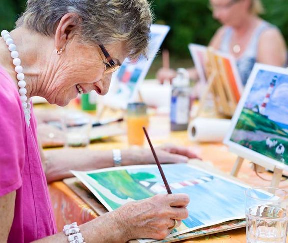 Senior woman happily painting at an event