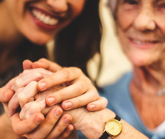Adult and elderly women holding hands and smiling