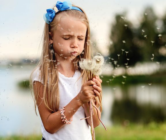Child blowing dandelion fluff