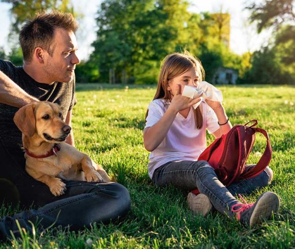 Girl in park with allergies, her dad, and their dog