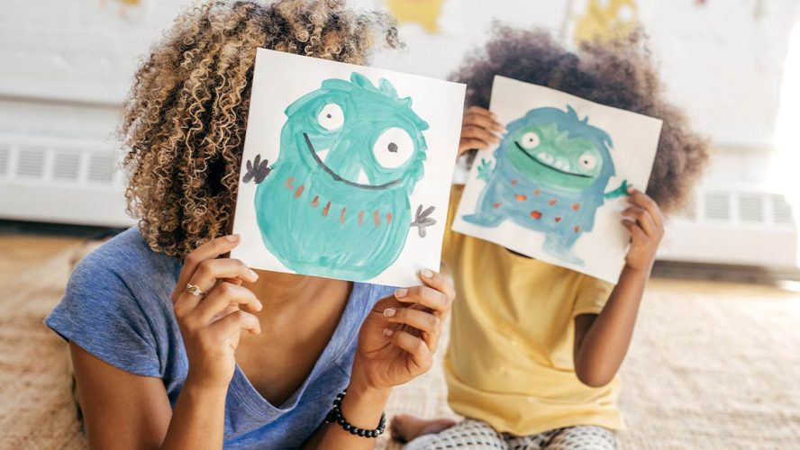 Mom and child holding drawings of cute monsters in front of their faces