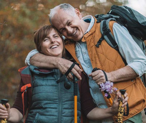 Senior couple grinning while on a hike
