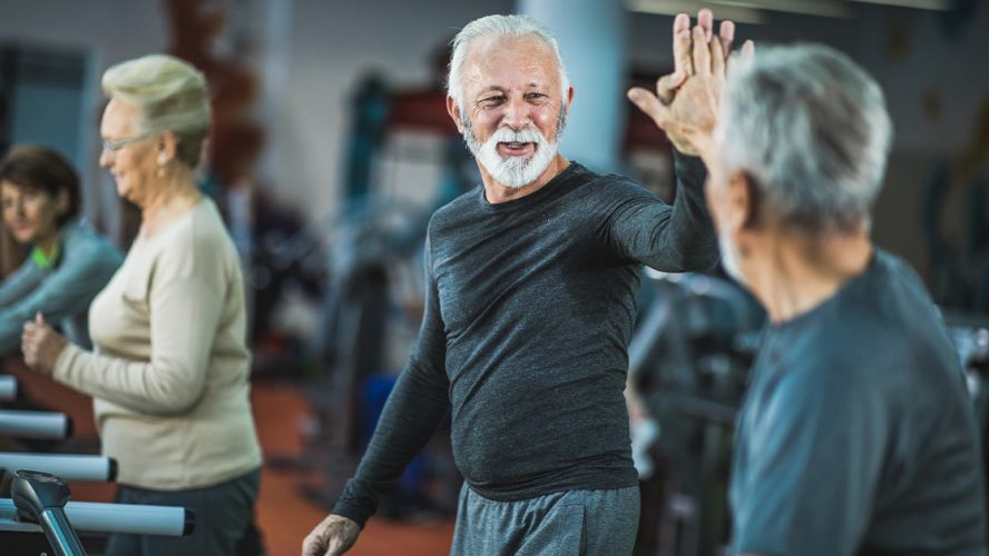 Two senior men high-fiving at the gym