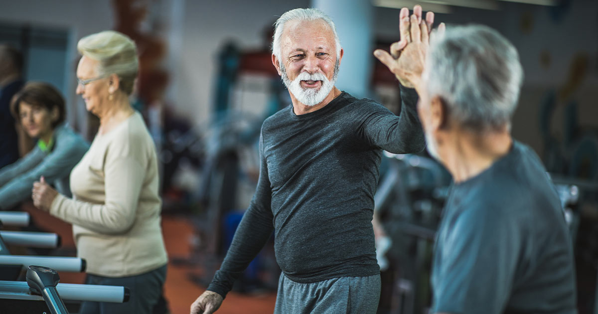 Two senior men high-fiving at the gym