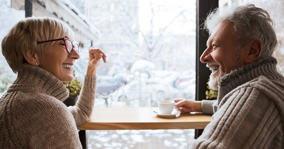 Two seniors smiling over a cup of coffee