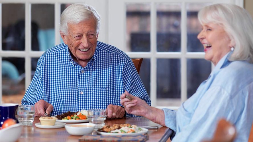Two happy seniors sharing a meal at home