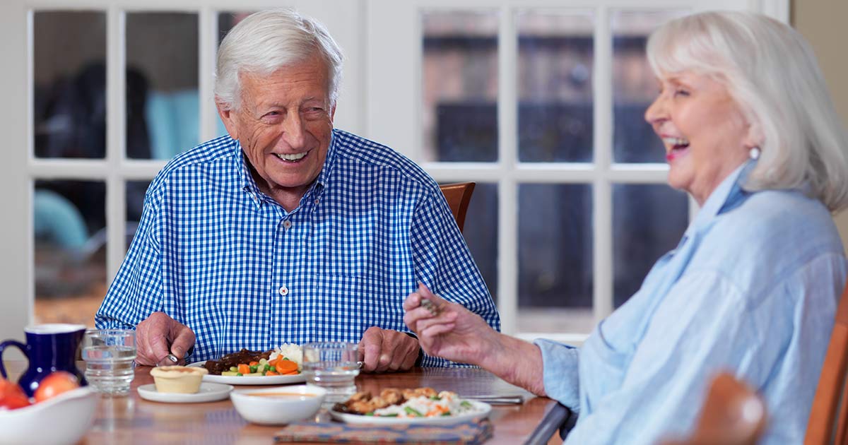 Two happy seniors sharing a meal at home