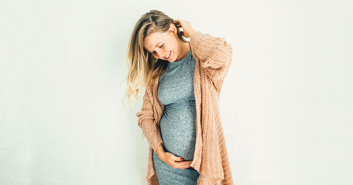Woman smiling and holding her pregnant belly