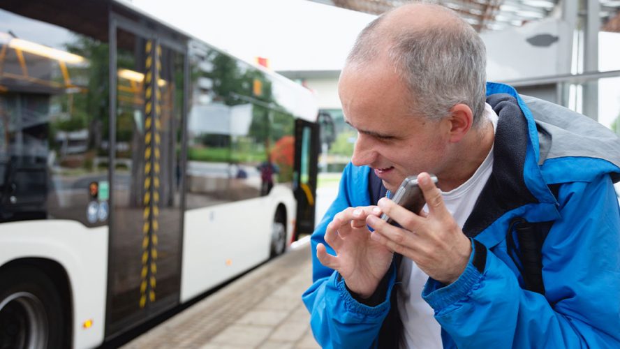 Blind man using cellphone at bus stop