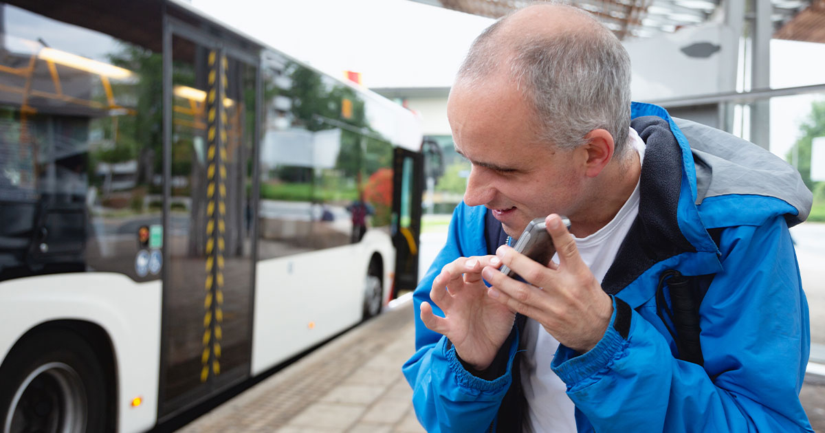 Blind man using cellphone at bus stop