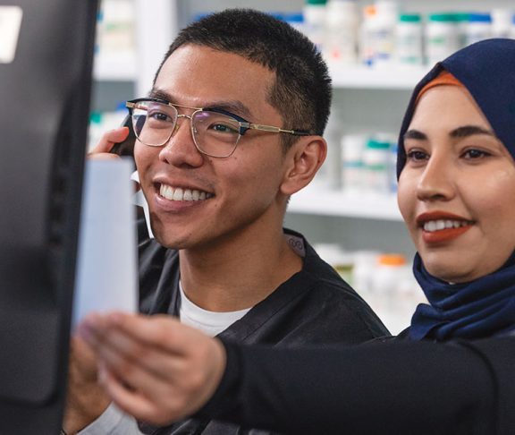 Two young pharmacy technicians working and smiling