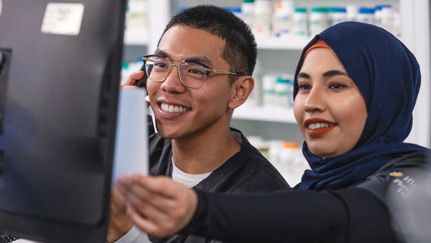 Two young pharmacy technicians working and smiling