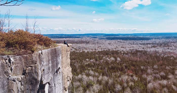 Jennifer Gauthier sitting on a cliff overlooking an escarpment