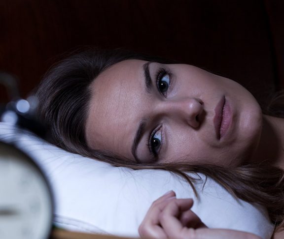 Woman staring at a clock and unable to sleep