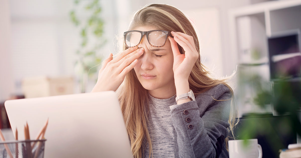 Woman working at a computer and rubbing her eyes