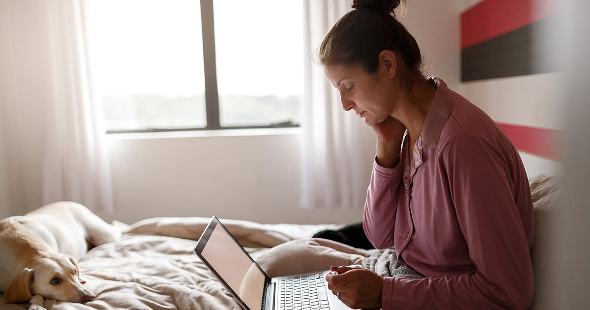 Woman sitting on a bed and using a laptop