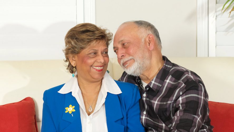 Two middle-aged people smiling at each other, one wears a CCS daffodil pin