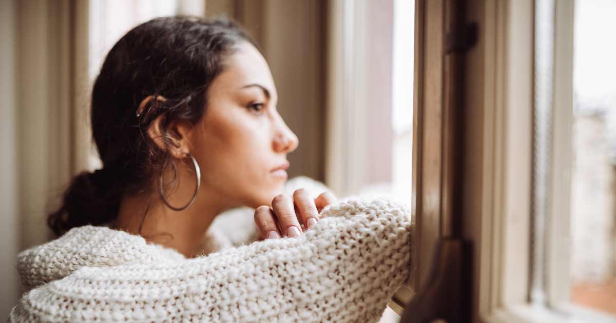 University student looking out of her window with a sad expression