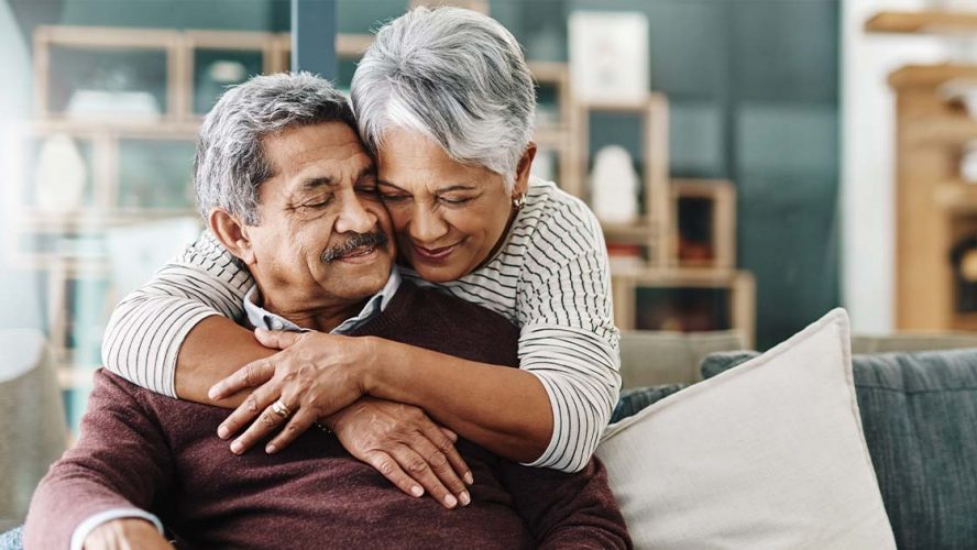 Elderly couple hugging in their home