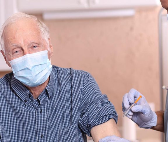 Senior man wearing face mask and receiving vaccination