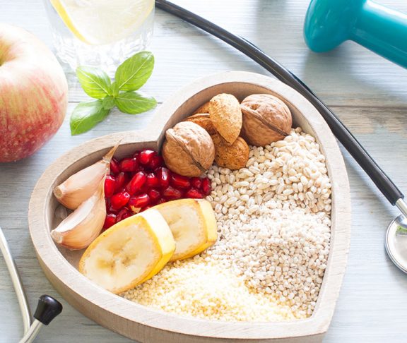 A bowl filled with nutrient rich foods placed in the middle of a stethoscope and dumbell