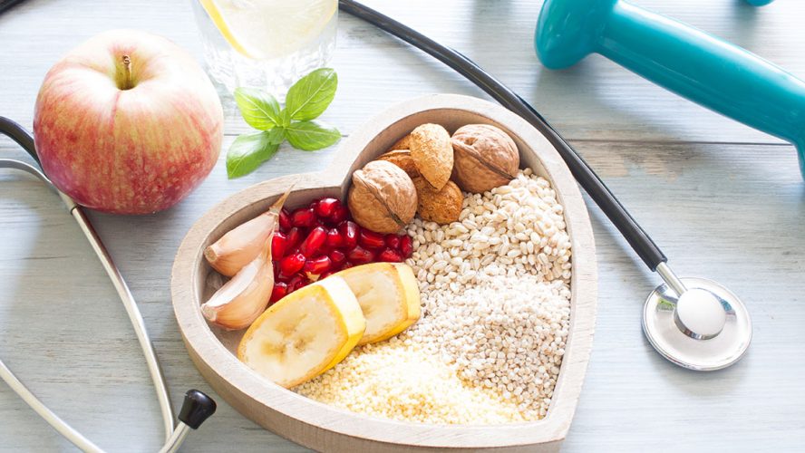 A bowl filled with nutrient rich foods placed in the middle of a stethoscope and dumbell