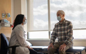 old man with mask talking to doctor