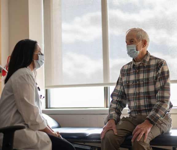 old man with mask talking to doctor