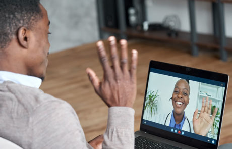Male black patient talking on video call to female african doctor