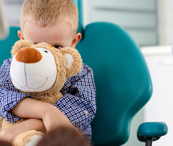 Kid holding onto stuffed bear-Alexion