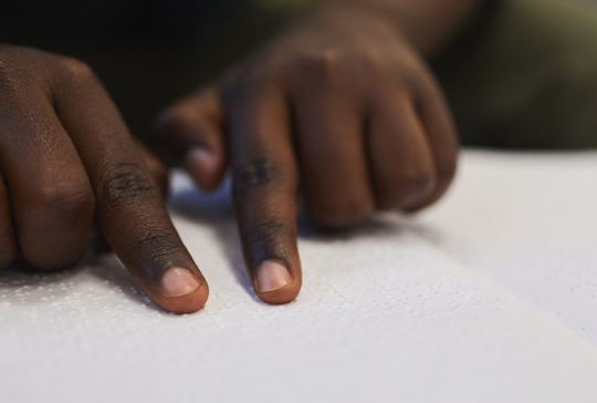 A close up of a child reading braille