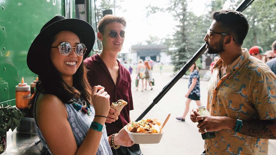 Three people in their twenties eating by a food truck