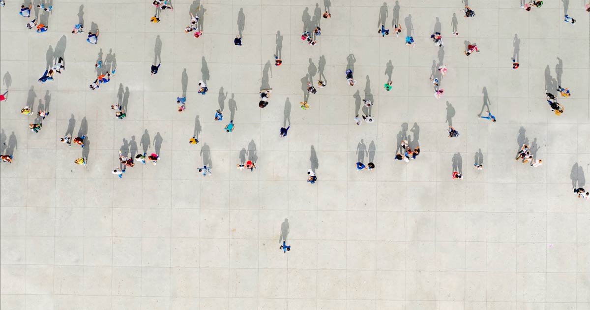 Aerial view of people gathered on concrete, one apart from the crowd