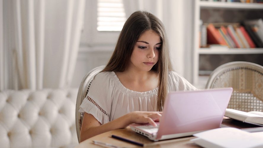 Teen girl working on a laptop at home