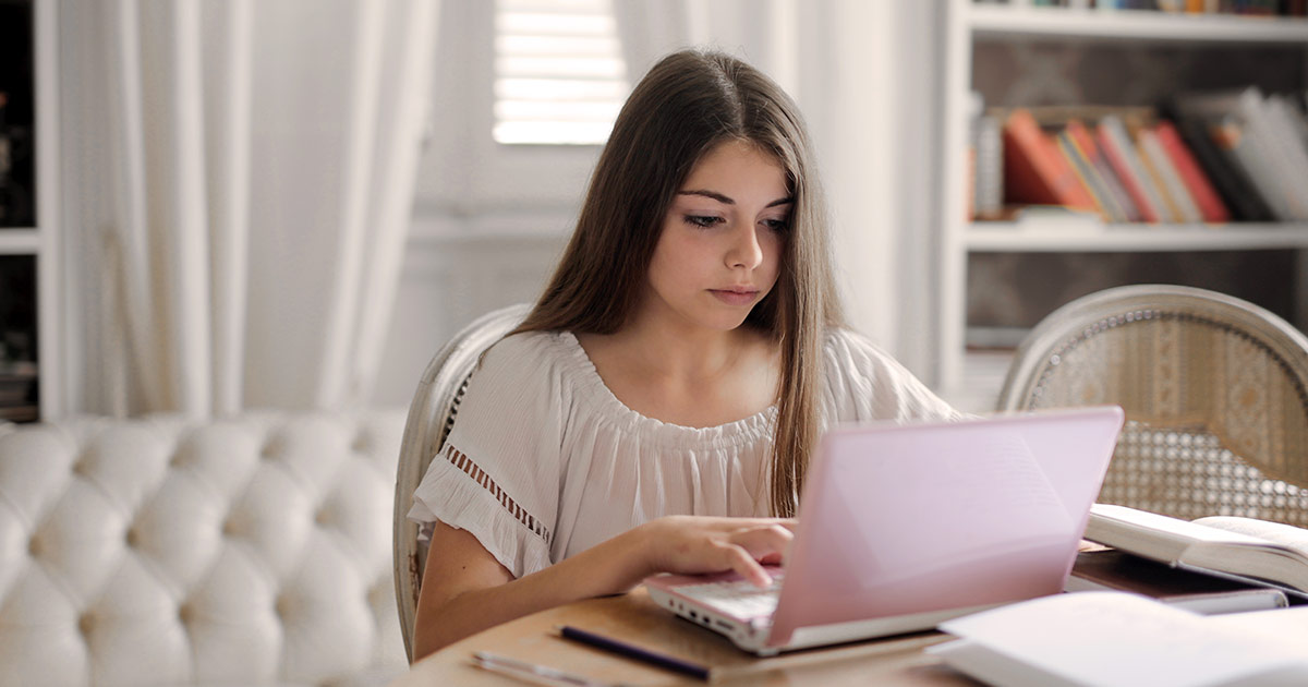 Teen girl working on a laptop at home