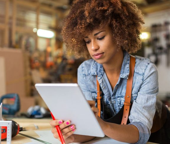 Black woman using digital tablet in her skilled trades workshop