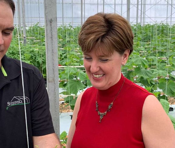 Minister Marie-Claude Bibeau speaking to a man in a greenhouse nursery