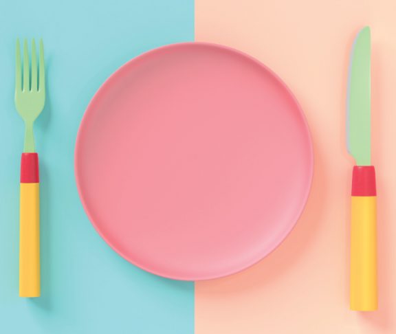 Pastel-coloured fork, plate, and knife laid on a table