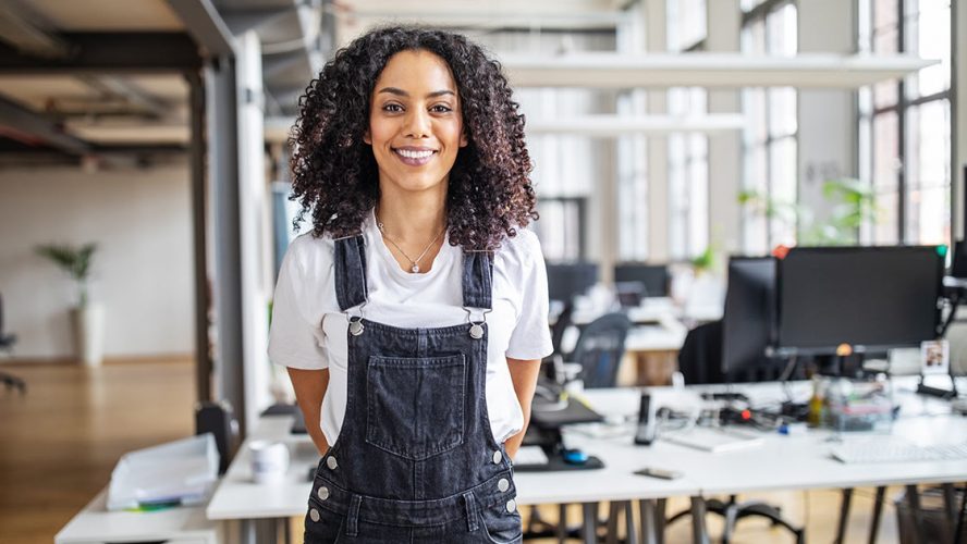 Smiling professional woman in an office wearing overalls