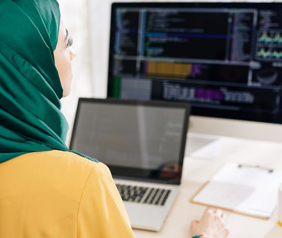 Woman in an emerald hijab programming on her computer